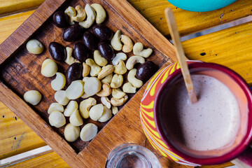Wooden plate with cashew nuts, macadamia, nuts covered in chocolate and coffee