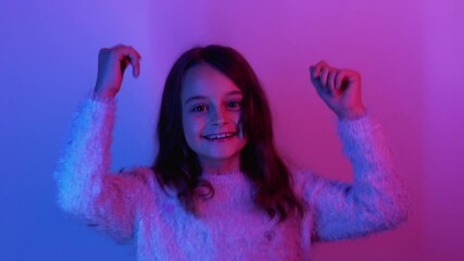Happy kid. Fun childhood. Positive lifestyle. Excited joyful amused little cute girl enjoying jumping dancing smiling in pink blue neon light on bright background.