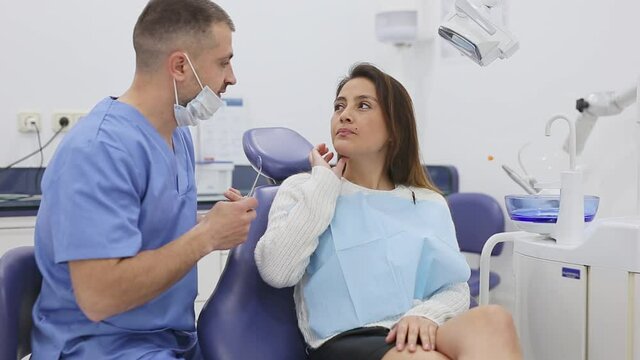 Dentist talking to female patient complaining of toothache at dentist office