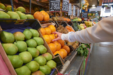 A hand grabbing an orange at a fruits and vegetable market