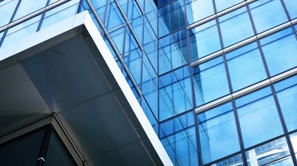 Obraz premium Abstract closeup of the glass-clad facade of a modern building covered in reflective plate glass. Architecture abstract background. Glass wall and facade detail. Velvia graphic filter.