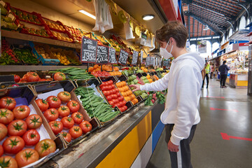 A young Caucasian guy wearing a sanitary mask grocery shopping - concept of the new normal