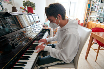 A shallow focus shot of a g playing the piano wearing a sanitary mask-concept of the new normal