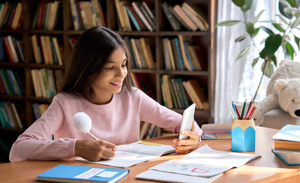 Happy smiling indian latin child student holding cell phone watching online learn class video call. Study from home virtual classroom using mobile app for distance study. - Powered by Adobe
