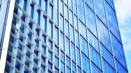 Abstract closeup of the glass-clad facade of a modern building covered in reflective plate glass. Architecture abstract background. Glass wall and facade detail. Velvia graphic filter.