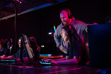 A pretty asian woman and a guy spend a date in a computer club, play computer games under the supervision of an experienced esports player
