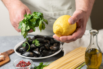 Fresh clams mussels, spaghetti, lemon and parsley. men's hands hold spaghetti, ingredients for seafood pasta. recipe for traditional Italian food pasta