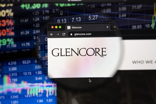 Glencore company logo on a website with blurry stock market developments in the background, seen on a computer screen through a magnifying glass