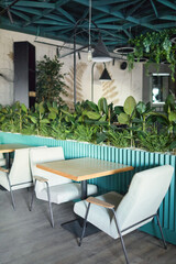 Vertical background image of eco friendly cafe interior with focus on cozy seating area with armchairs and table decorated by fresh green plants, copy space