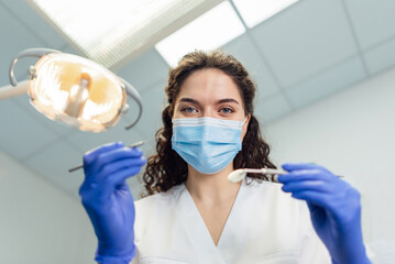 the dentist bent over the patient holding the instrument in his hands