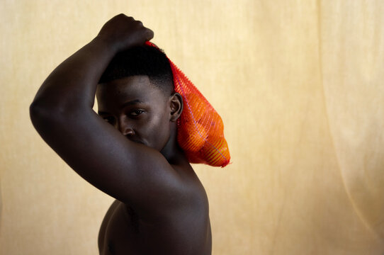 Young black man holds sack of oranges