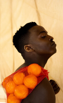 Young black man holding sack of oranges