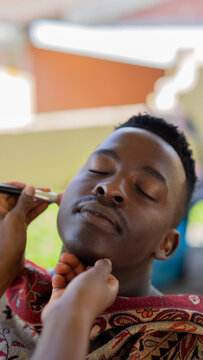 Young black man getting makeup done