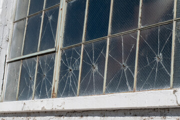 A  row of broken window panes damaged by gunshots.
