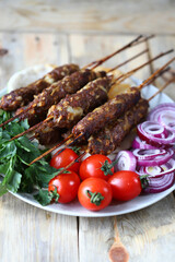Appetizing lula kebab on sticks with onion rings and herbs. Ramadan.