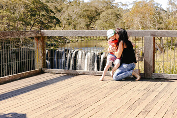 Mother and son snuggling together with waterfall in background