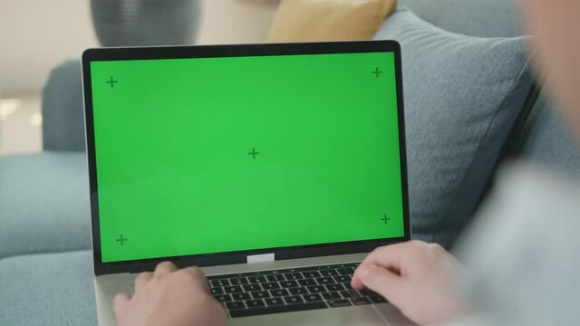 Male Working On Laptop With Green Screen Display

