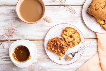 Homemade cake with raisins, almonds, soft caramel and a cup of coffee on a white wooden background. top view, close up.