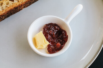 Freshly homemade baked sour dough rye bread sliced and served with jam and butter on white plate.