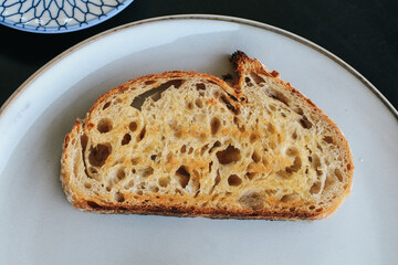 Freshly homemade baked sour dough rye bread sliced and served with jam and butter on white plate.