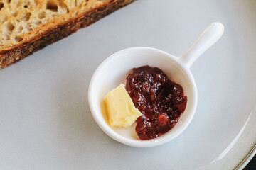 Freshly homemade baked sour dough rye bread sliced and served with jam and butter on white plate.