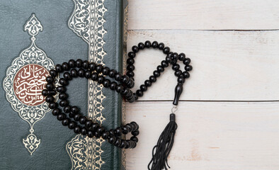 Holy Islamic Book Koran with rosary beads on wooden background. Quran with written arabic calligraphy meaning of Al Quran. Ramadan Mubarak. Ramadan kareem. 