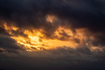 Dark summer sunrise featuring sun, clouds, and light