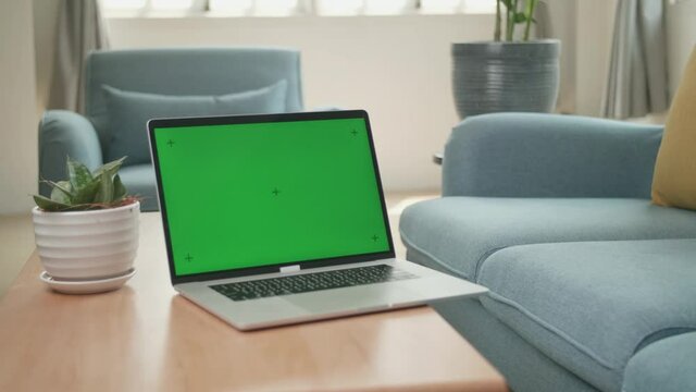 Laptop With Green Screen Display On Table At Home Living Room