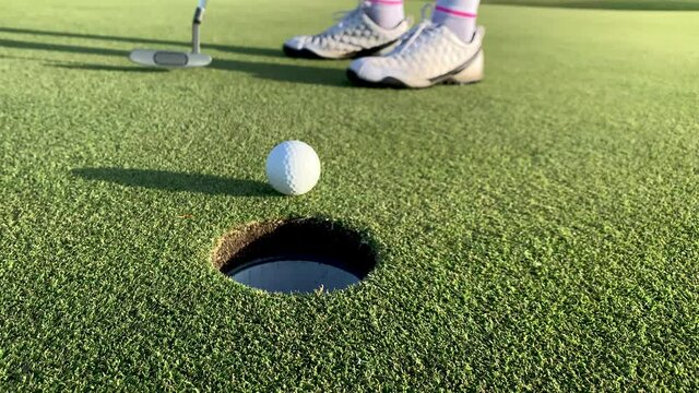 Woman Putting a Golf Ball into a Hole