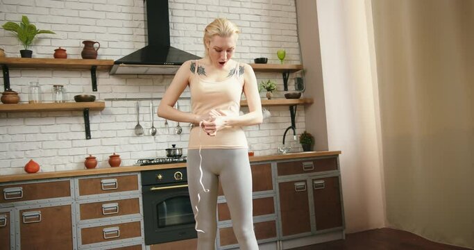 Skinny blond caucasian woman measures her waist in the mirror using a tape measure. She is dieting and happy with weight loss