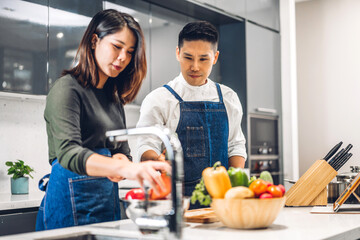 Young asian family couple having fun cooking together with fresh vegetable salad on table.Happy...