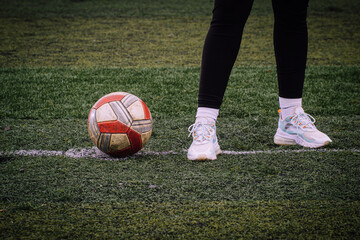 Woman standing inside a soccer field next to a ball