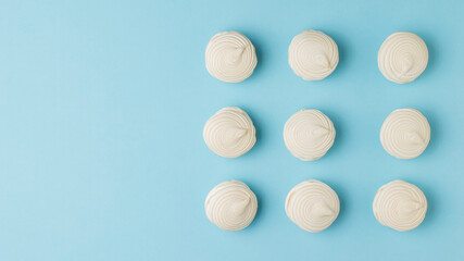 Nine fresh meringues on a blue background.