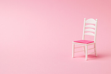 White chair with red seat on pink background.