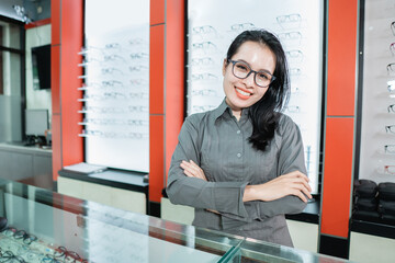 a beautiful woman posing wearing glasses against the background of an eyeglass display case in an...