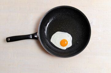 Freshly fried egg in black pan, top view 