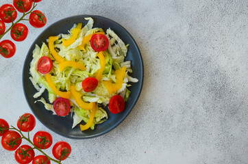 fresh summer salad of peking cabbage, yellow sweet bell pepper and cherry tomato in a ceramic plate, vegetarian food and diet