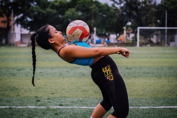 Woman doing series with soccer ball on synthetic turf