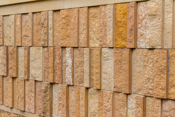 This image shows a rough texture stone wall background with attractive narrow vertical kasota limestone blocks in varying widths, and shades of brown and beige