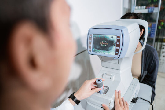 a male ophthalmologist is operating an eye computer for a female patient to examine the patient's eyes at an eye clinic