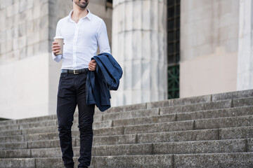 Businessman holding a cup of coffee on way to work.