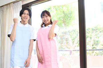 ガッツポーズをするエプロン姿の男女
