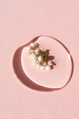 A drop of cosmetic gel with flower on a pink background.