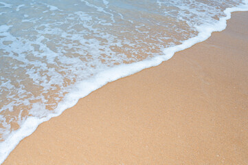 Fototapeta na wymiar Wave foam of sea on brown sandy beach in summer season, Thailand