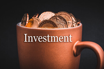 INVESTMENT text with Coins in cups on black background. Tax, Savings, Profit and Investment Concept