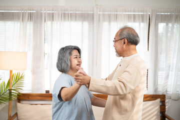 Obraz premium Asian senior couple dancing together in free time at the living room.