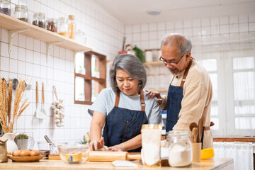 Asian senior couple helping each other for homemade bakery cooking.