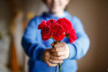 Closeup of hands of preteen kid boy holding bunch of clove flowers. Child congrats and presents...