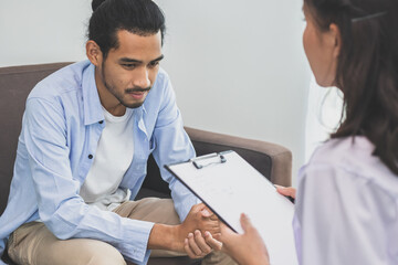 Obraz premium Asian young asian man, male has mental symptoms which must have been therapy and stress, sitting on couch to consult to psychologist during the session take notes to find out how to treat therapist.