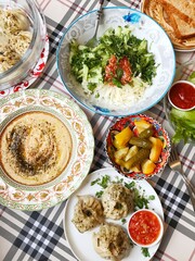 homemade manti, homemade hummus and fresh vegetable salad on the table. home-made lunch.
